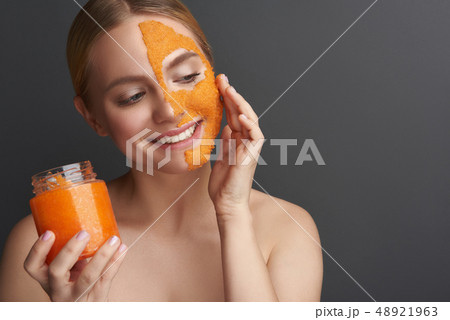 Happy woman applying peel off mask from the jar and smiling Happy woman applying peel off mask from the jar and smiling 48921963