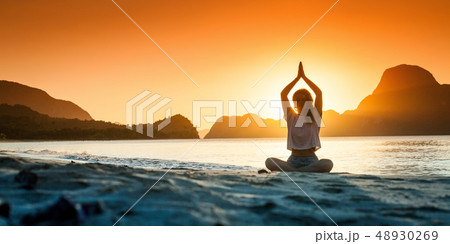 Silhouette of young girl doing yoga at sunset time Silhouette of young girl doing yoga at sunset time 48930269