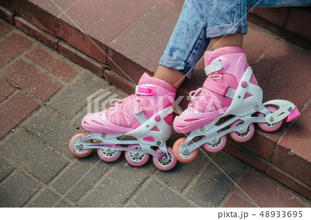 Close up photo of woman's legs wearing cute pink roller blades 48933695