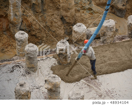 Worker with pipe pouring concrete 48934104