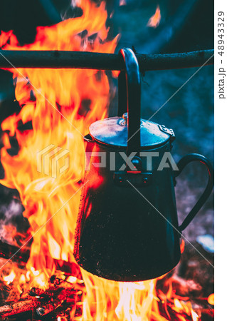 Old Iron Camp Kettle Boils Water On A Fire In Forest. Bright Flame Fire Bonfire At Dusk Night. Old Iron Camp Kettle Boils Water On A Fire In Forest. Bright Flame Fire Bonfire At Dusk Night. 48943329