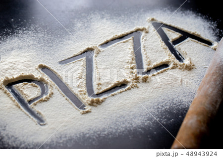 Pizza word written in flour on black table Pizza word written in flour on black table 48943924