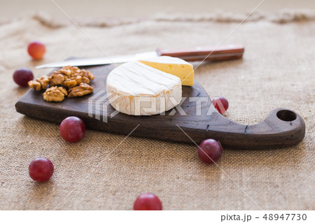 Brie type of cheese. Camembert cheese. Fresh Brie cheese on a wooden board with nuts and grapes 48947730