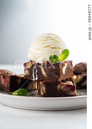 Chocolate brownie with vanilla ice cream, rasberry and mint on a white background. Copy space. Chocolate brownie with vanilla ice cream, rasberry and mint on a white background. Copy space. 48948777