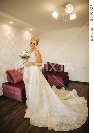 Elegant bride in beautiful wedding dress with bouquet at home. Blond hair woman with beautiful Elegant bride in beautiful wedding dress with bouquet at home. Blond hair woman with beautiful 48949027