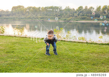 Chilhood, people concept - young boy playing with soap bubbles 48949269
