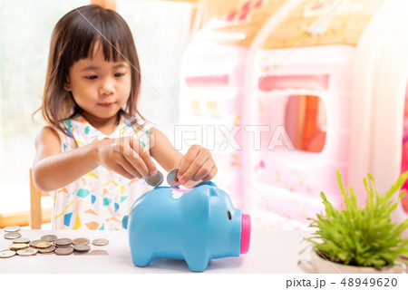 Asian girl putting coin in the piggy bank Asian girl putting coin in the piggy bank 48949620