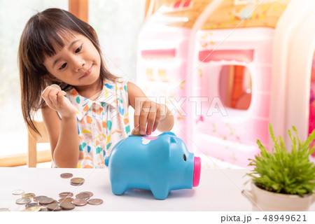 Asian girl putting coin in the piggy bank Asian girl putting coin in the piggy bank 48949621