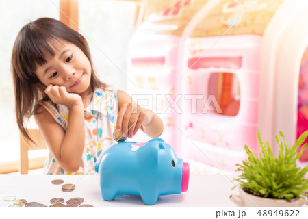 Asian girl putting coin in the piggy bank for Asian girl putting coin in the piggy bank for 48949622