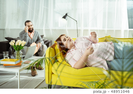 Relaxed overweight young woman lying on sofa 48951046