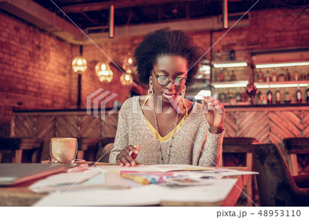 Serious African-American female thoroughly looking at papers in cafeteria Serious African-American female thoroughly looking at papers in cafeteria 48953110
