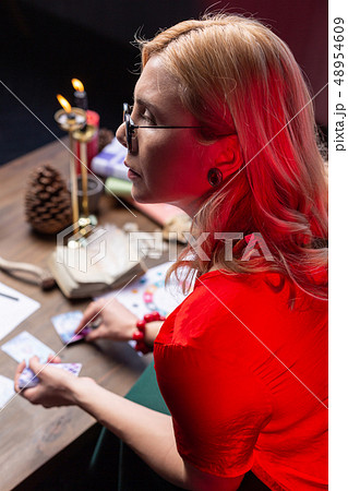 Blonde-haired diviner with wavy hair practicing at home sitting at the table Blonde-haired diviner with wavy hair practicing at home sitting at the table 48954609