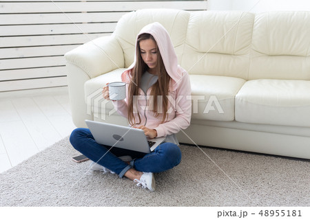 People, freelance and technologies concept - young woman drinking tea on the floor. Laptop and 48955181