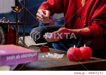 Predictor wearing red cardigan reading oracle cards sitting in armchair Predictor wearing red cardigan reading oracle cards sitting in armchair 48955257
