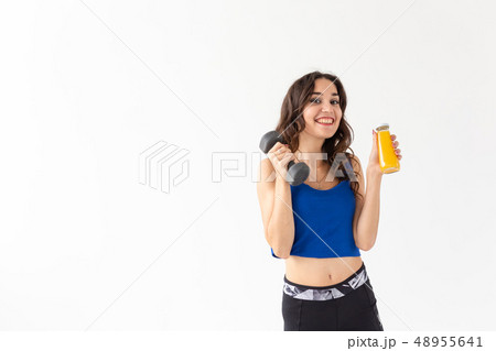 Sport, healthy lifestyle, people concept - young woman holds bottle of juice and a dumbbell on white 48955641