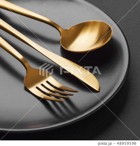 Gold cutlery set on black background Gold cutlery set on black background 48959596