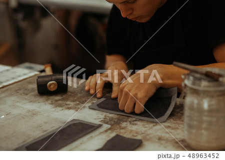 Close up of leather craftsman working with natural leather. Handmade master at work in local 48963452