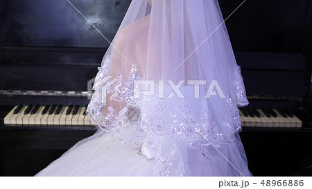 girl in a white dress plays the piano. The bride performs a piece of music on the piano. music girl in a white dress plays the piano. The bride performs a piece of music on the piano. music 48966886