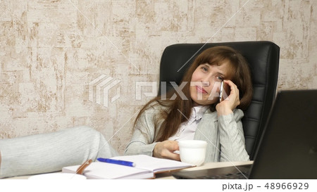 woman in office drinking coffee resting in workplace. beautiful businesswoman with phone sits in a woman in office drinking coffee resting in workplace. beautiful businesswoman with phone sits in a 48966929