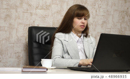beautiful girl sitting in chair in office and typing on laptop. young woman businesswoman working at 48966935