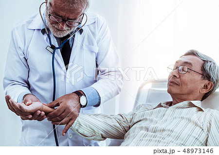 Mature doctor and senior patient in hospital ward. Mature doctor and senior patient in hospital ward. 48973146