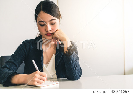 Beautiful young Asian woman writes on notebook. Beautiful young Asian woman writes on notebook. 48974063