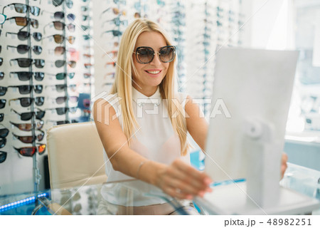 Female customer in sunglasses looks at the mirror 48982251