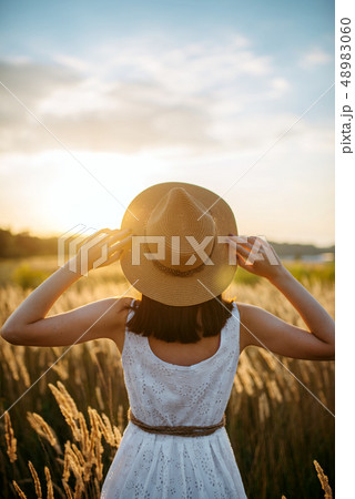 Woman in dress walking in wheat field on sunset Woman in dress walking in wheat field on sunset 48983060