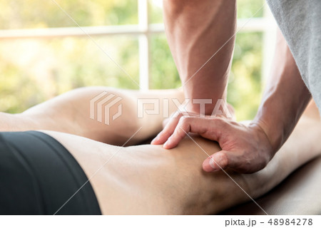 Male therapist giving leg massage to athlete 48984278
