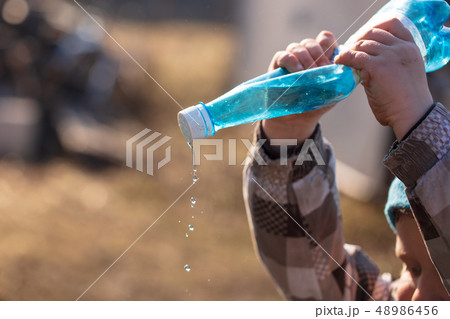 The boy is watering the bottle with water The boy is watering the bottle with water 48986456