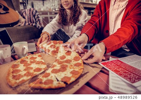 Close up of students taking pieces of pizza after studying together Close up of students taking pieces of pizza after studying together 48989526