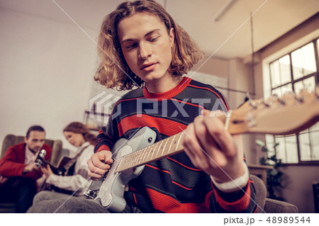 Music student wearing red and blue sweater playing the guitar Music student wearing red and blue sweater playing the guitar 48989544
