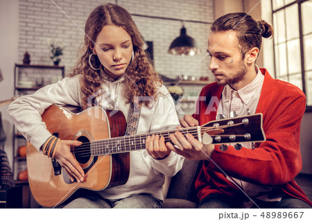 Teenage girl feeling excited while playing guitar for the first time 48989667