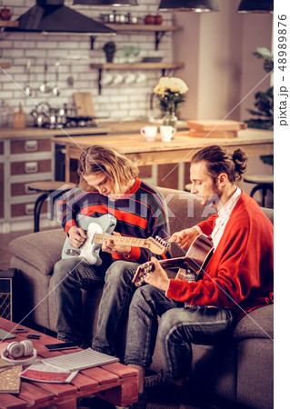 Participants of band sitting on sofa and playing music instruments 48989876