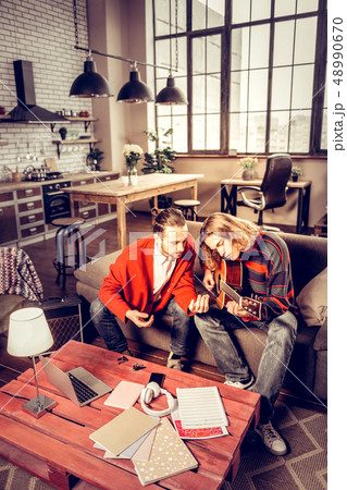 Two guitar players playing the music in their spacious apartment 48990670