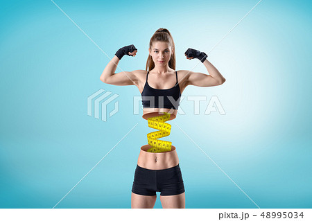 Young fit woman in short black gym top and shorts, in double bicep pose, upper body cut at waist and 48995034