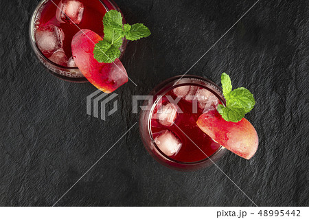 Overhead photo of vibrant red drinks with mint on black 48995442