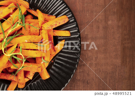 A closeup of roasted sweet potato fries on a black plate, shot from the top with copyspace A closeup of roasted sweet potato fries on a black plate, shot from the top with copyspace 48995521