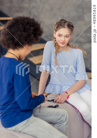Charming longhaired blonde teenager looking at her friend Charming longhaired blonde teenager looking at her friend 48995819