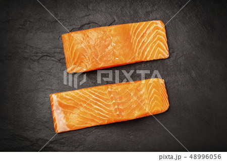 Two slices of salmon with on a black background with copy space, overhead photo Two slices of salmon with on a black background with copy space, overhead photo 48996056