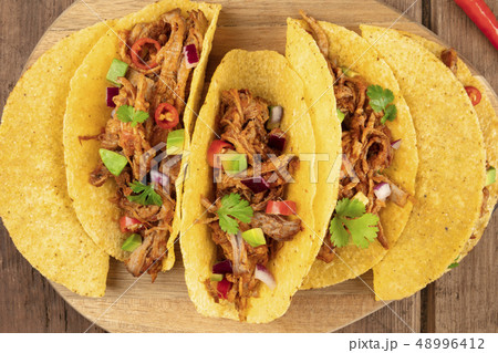 Closeup of Mexican tacos with pulled meat, avocado, chili peppers, cilantro Closeup of Mexican tacos with pulled meat, avocado, chili peppers, cilantro 48996412