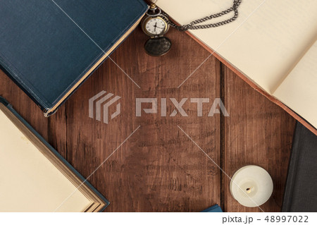 Overhead photo of books on dark background with vintage watch, candle, and copy space 48997022