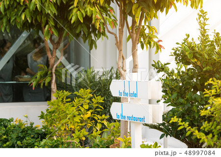 Wooden sign in the garden showing the way to the hotel and restaurant Wooden sign in the garden showing the way to the hotel and restaurant 48997084