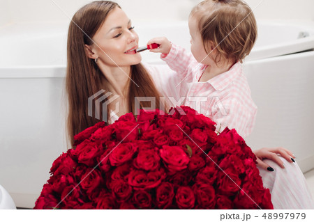 Beautiful mother posing with girl and big bouquet 48997979