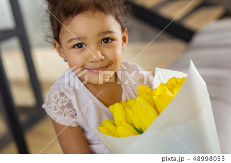 Positive delighted kid demonstrating bouquet of tulips Positive delighted kid demonstrating bouquet of tulips 48998033