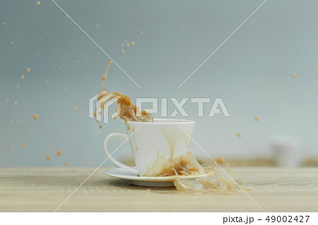 Splash in white cup of coffee on wooden table 49002427