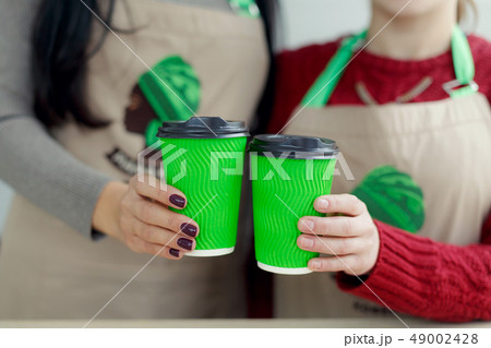 two barista in aprons is holding hot coffee in two barista in aprons is holding hot coffee in 49002428
