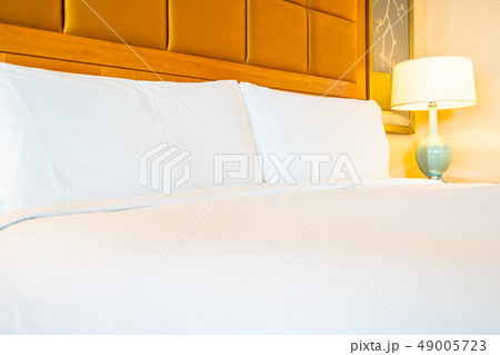White comfortable pillow on bed with table light lamp decoration in hotel bedroom 49005723