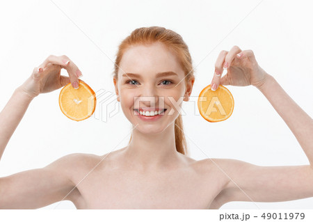 Great food for a healthy lifestyle. Beautiful young shirtless woman holding piece of orange standing 49011979