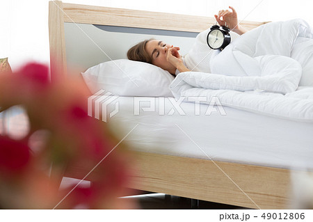 Sleepy young woman trying close alarm clock. 49012806